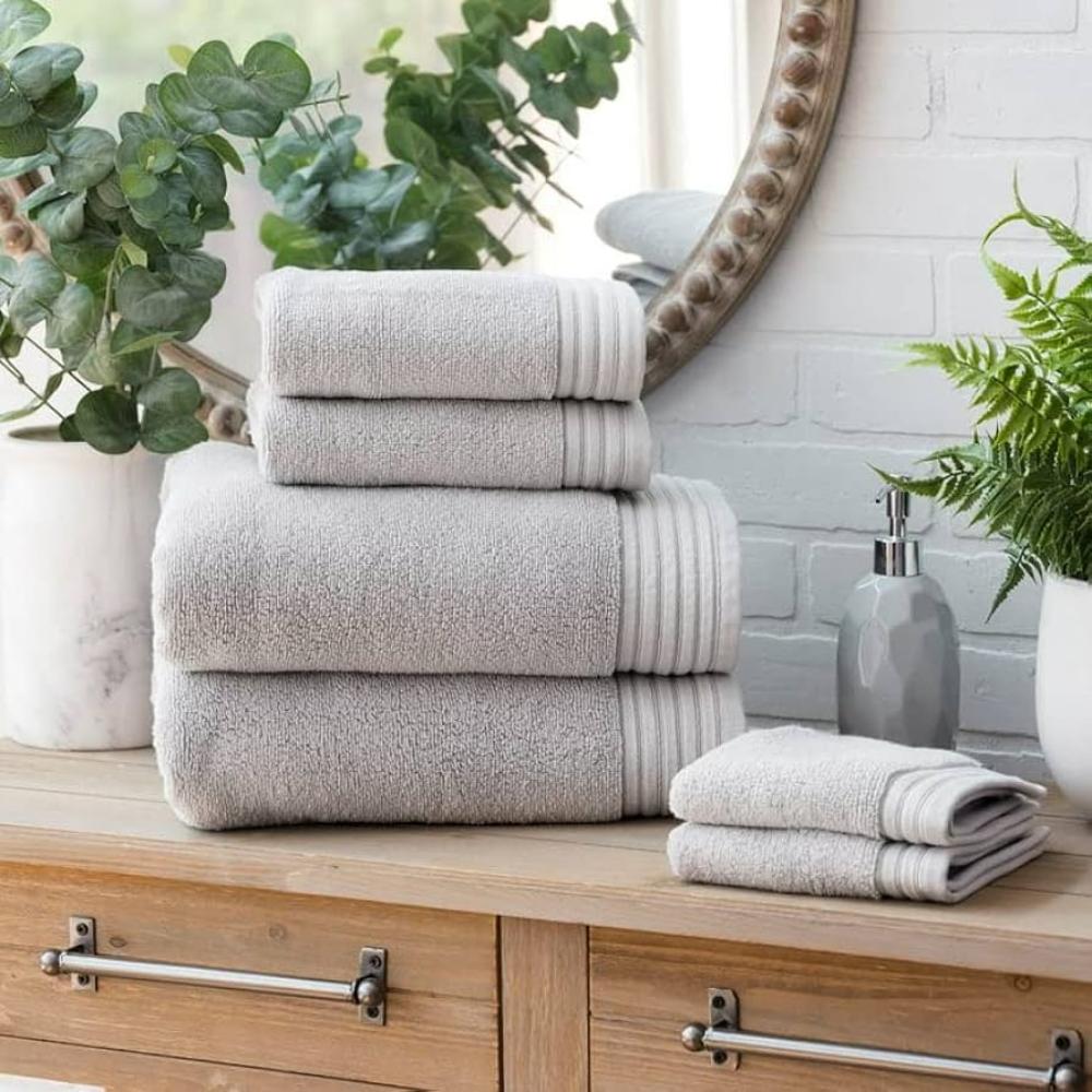 Grey folded bath towel neatly arranged on a countertop in a clean, modern bathroom setting.