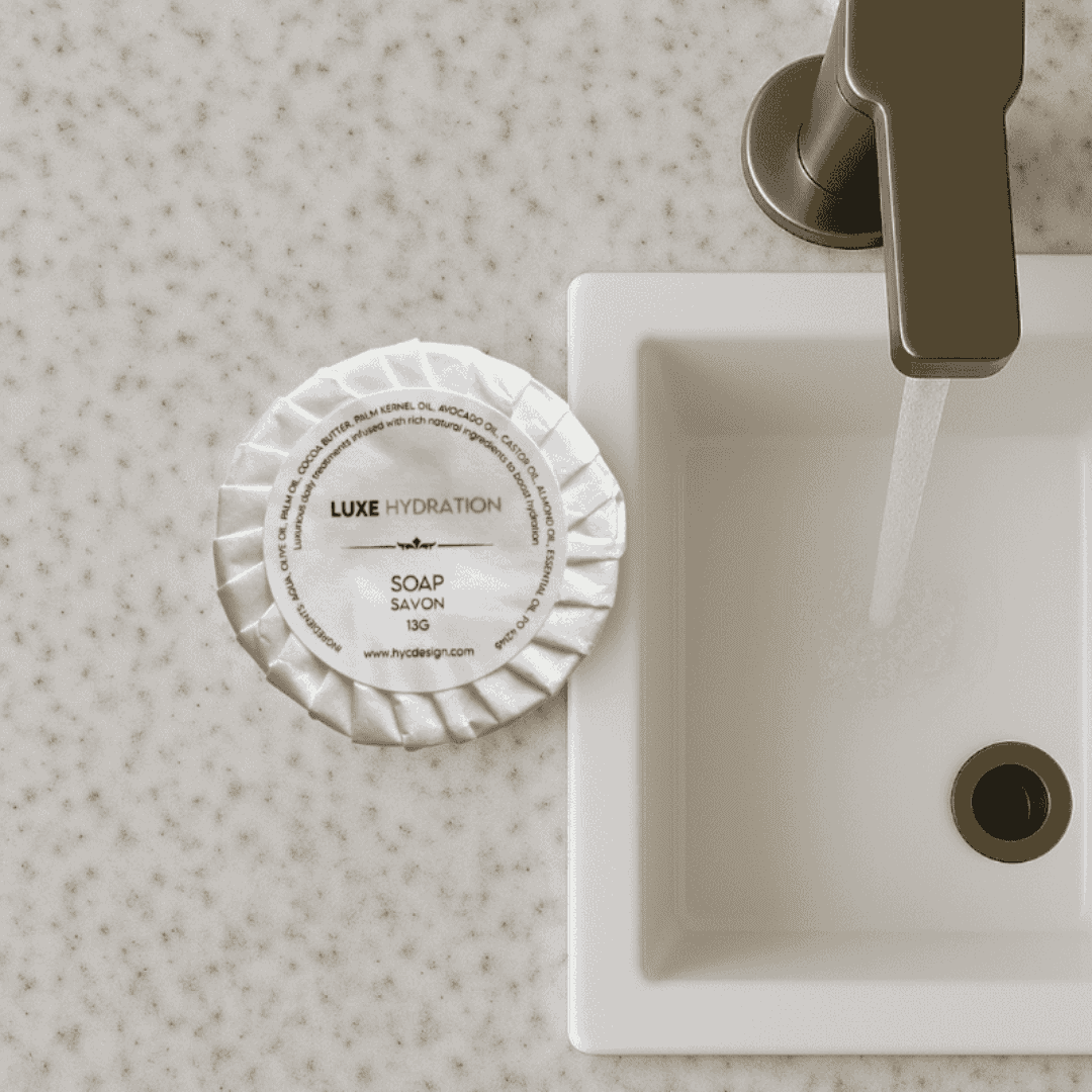 Luxe Hydration Soap 13g on hotel sink, a compact and elegant addition to guest bathroom essentials.