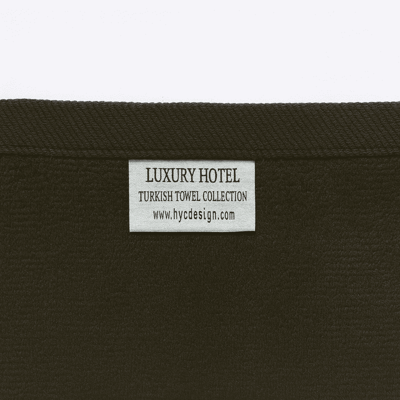 Close-up of Luxury Hotel Turkish Towel Collection label by HYC Design, showing brand tag on black cotton towel.