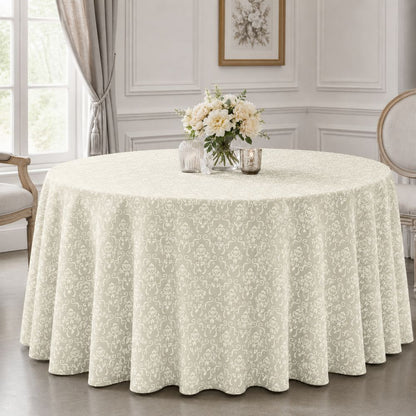 Ivory patterned round tablecloth displayed on an elegant round table with floral centrepiece in a bright, classic dining room.