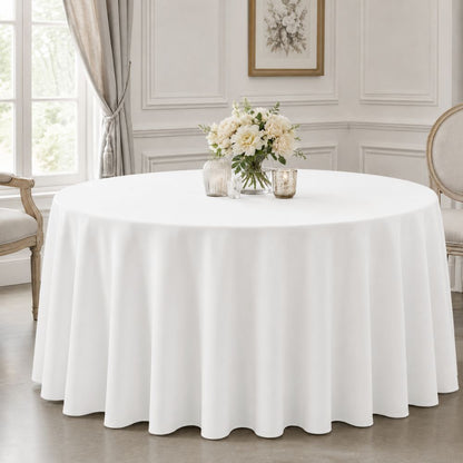 White round tablecloth covering a dining table with soft floor-length draping and floral décor in a bright formal room.