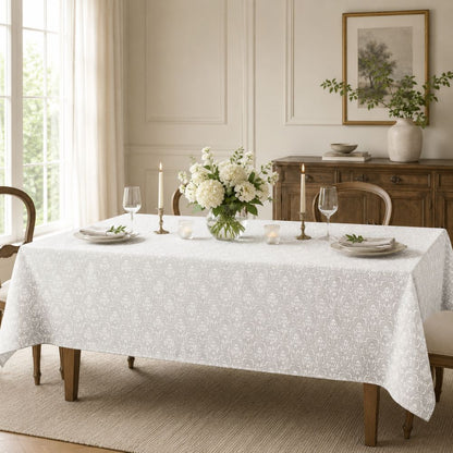 White patterned rectangular tablecloth displayed on a dining table with floral centrepiece, candles and classic dining room décor.