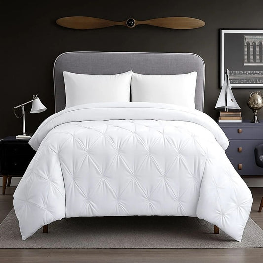 White pinch-pleat comforter styled on a modern bed with crisp white pillows for a clean, bright and luxurious bedroom appearance.