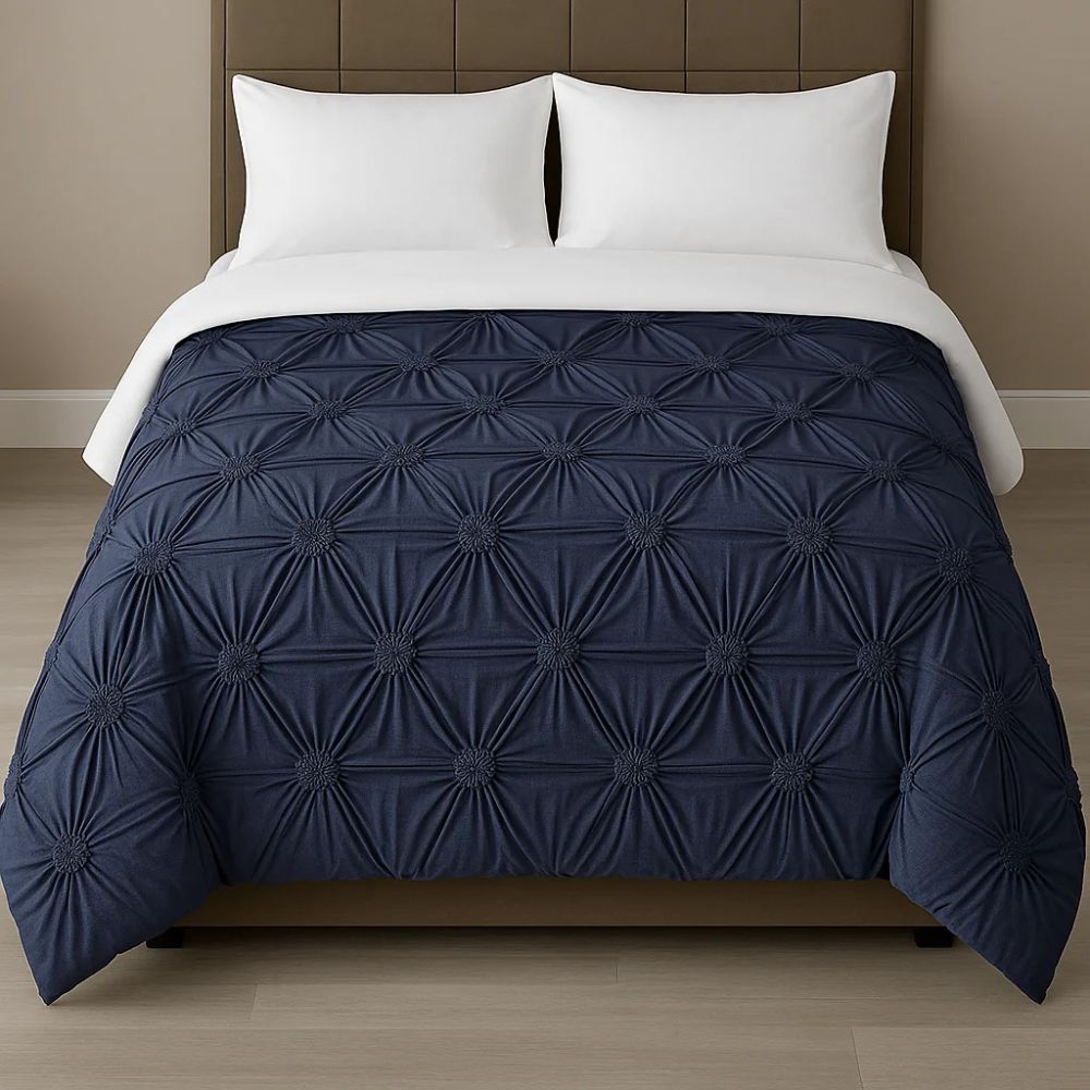 White pinch-pleat comforter styled on a modern bed with crisp white pillows for a clean, elegant bedroom look.