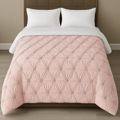 Light blush pink pinch-pleat comforter displayed with crisp white pillows for a soft and elegant bedding style.
