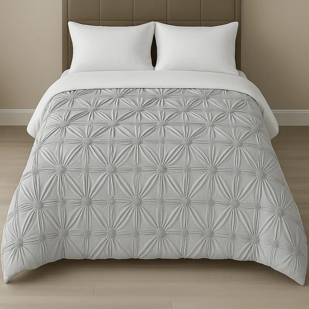Silver grey pinch-pleat comforter displayed on a neatly made bed with white pillows for a refined and contemporary style.