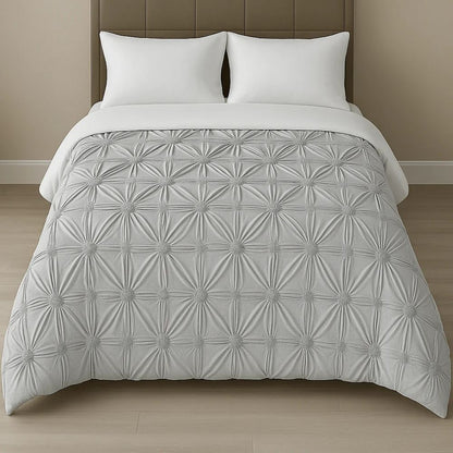 Silver grey pinch-pleat comforter displayed on a neatly made bed with white pillows for a refined and contemporary style.