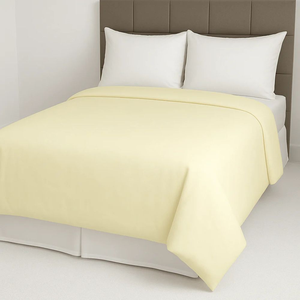 Pale yellow duvet cover styled on a neatly made bed with white pillows for a light and cheerful bedroom look.