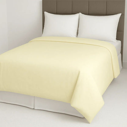 Pale yellow duvet cover styled on a neatly made bed with white pillows for a light and cheerful bedroom look.