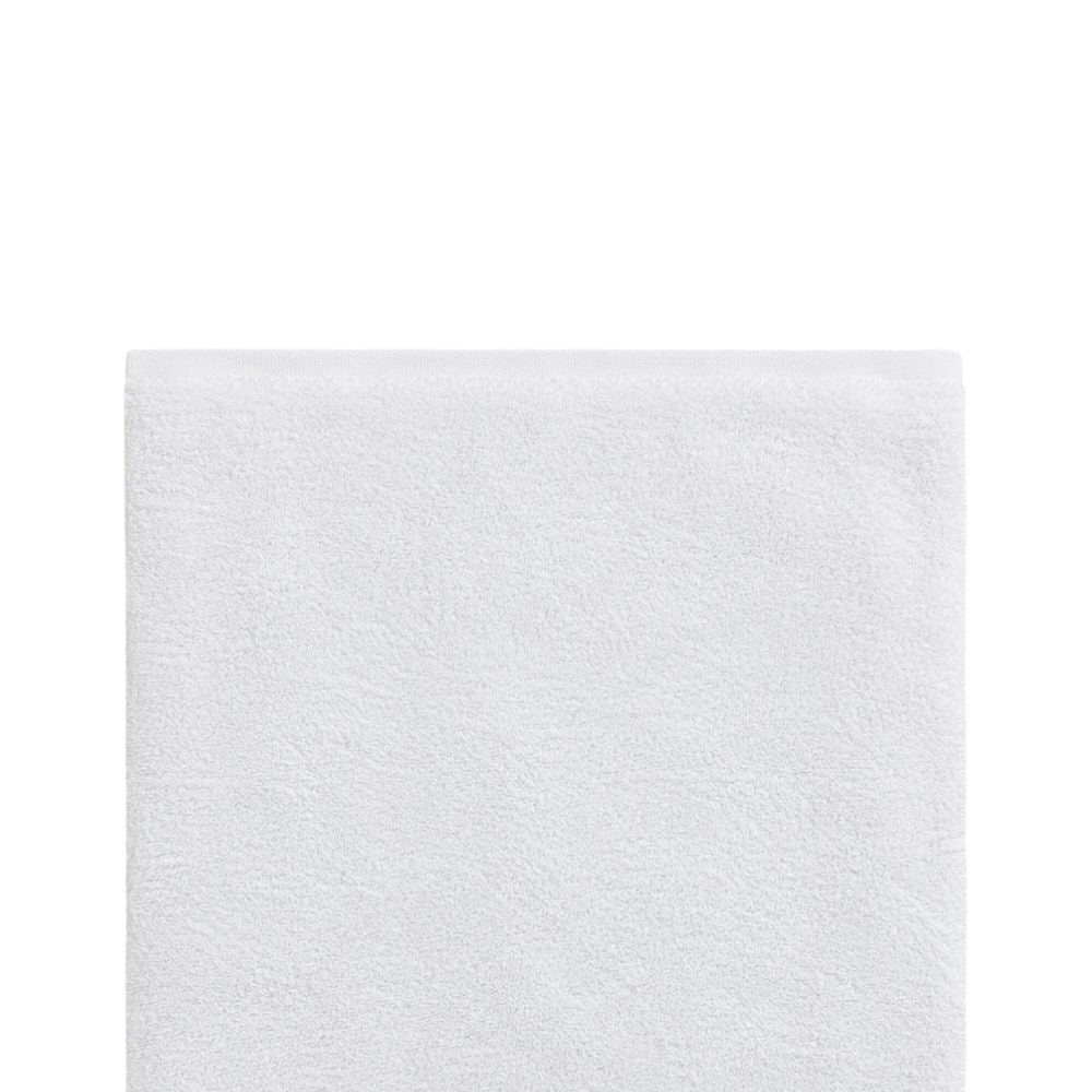 Close-up of a soft white bath towel on a white background, highlighting the plush terry texture and neatly finished top border.