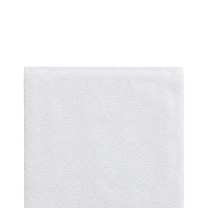 Close-up of a soft white bath towel on a white background, highlighting the plush terry texture and neatly finished top border.