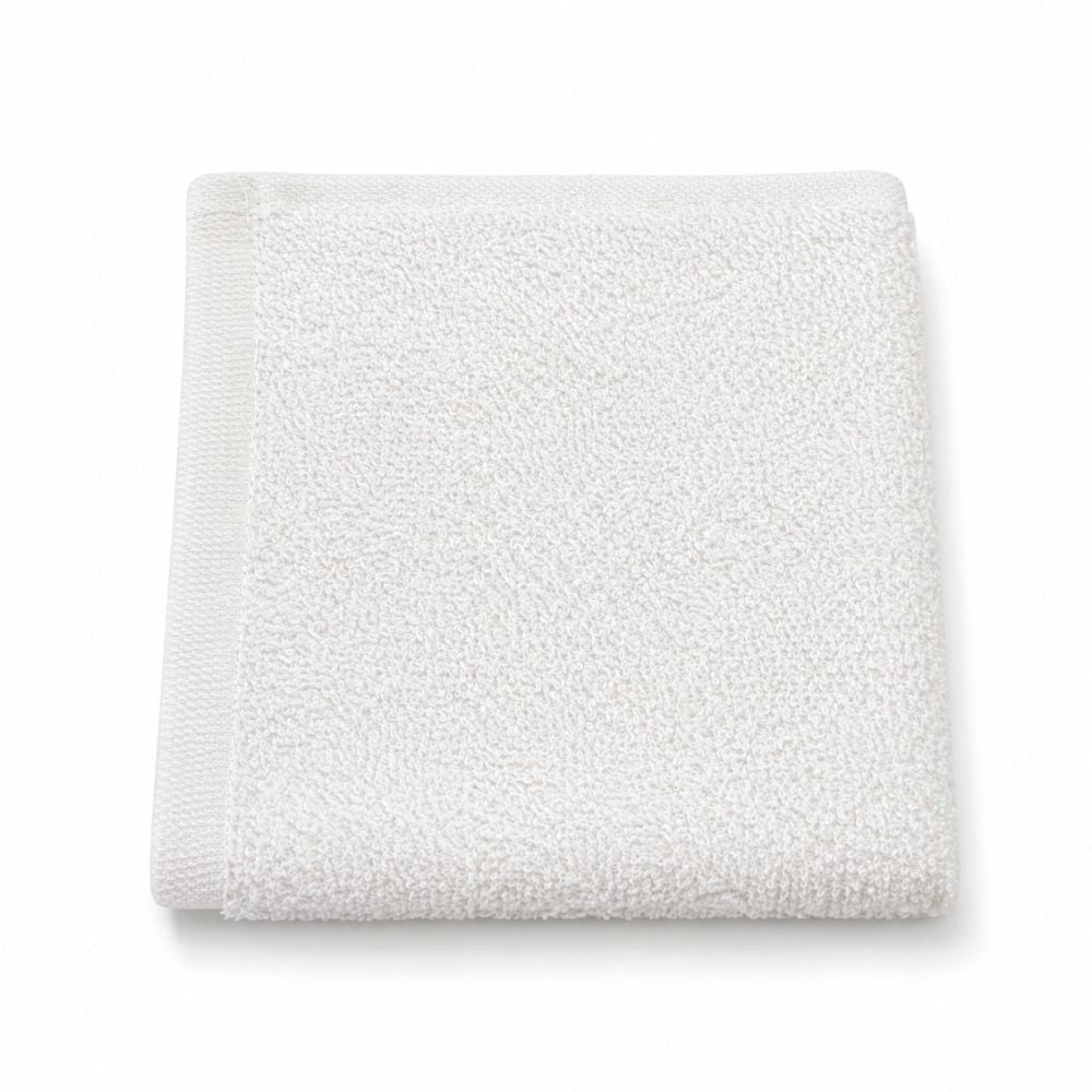 Folded white terry washcloth with a soft textured surface and clean hemmed border, ideal for bathrooms, travel and daily care.