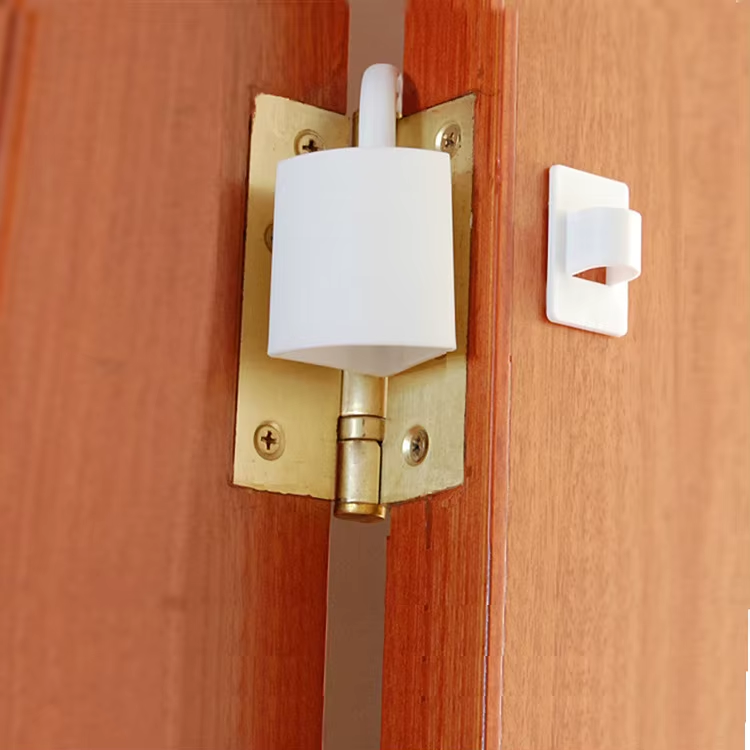 White plastic Hinge Buddy door stopper, slides over hinge to hold door open for housekeeping, janitorial, and maintenance use