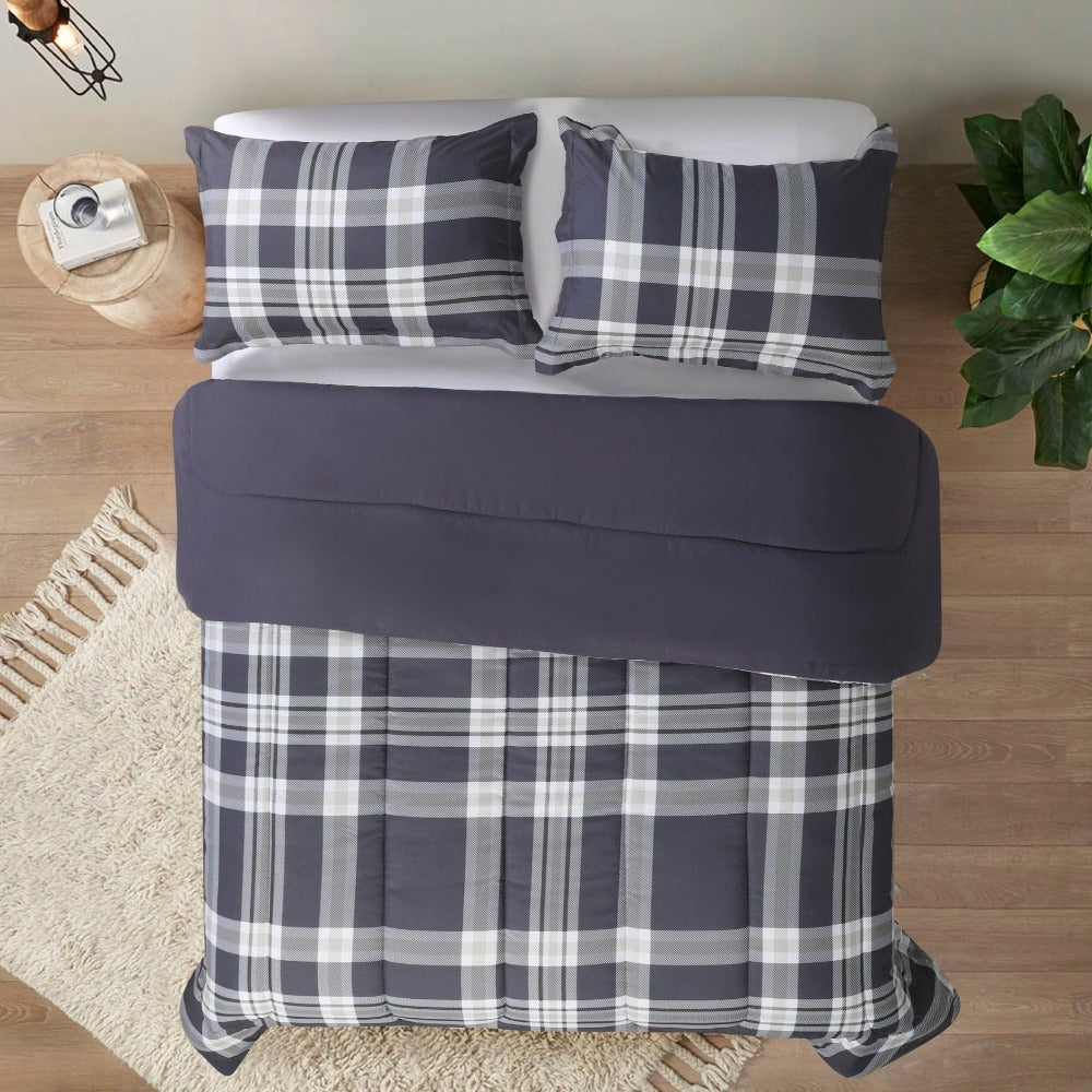 An inviting bed featuring a plaid comforter and pillows, perfect for a comfortable and restful sleep.