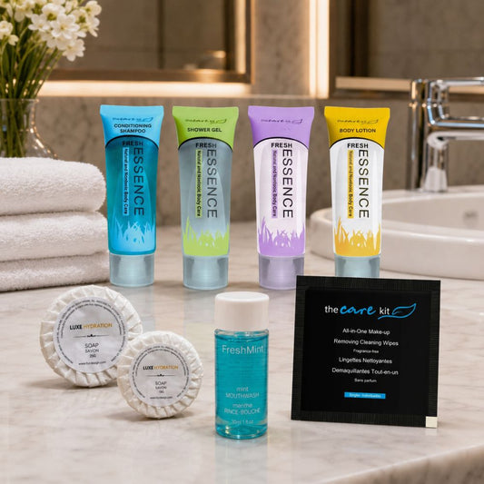 HYC Design Fresh Essence personal care set with shampoo, shower gel, body lotion, soaps, mint mouthwash and a makeup-removing wipe in a modern bathroom.
