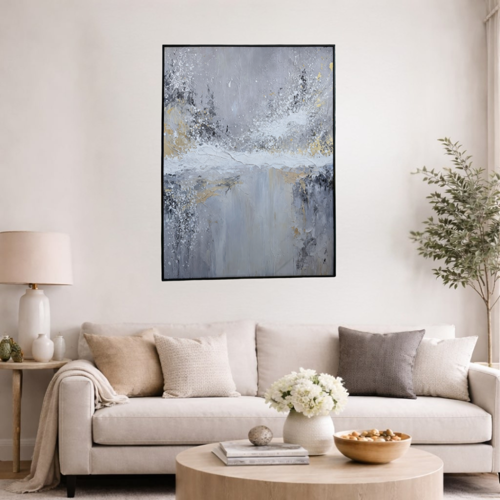 Abstract grey and white textured wall art with gold accents in a black frame, displayed in a modern living room interior