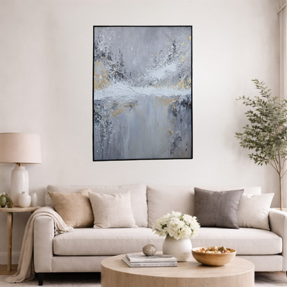 Abstract grey and white textured wall art with gold accents in a black frame, displayed in a modern living room interior