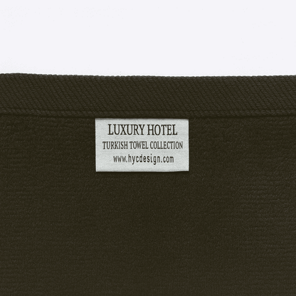 Close-up of Luxury Hotel Turkish Towel Collection label by HYC Design, showing brand tag on black cotton towel.