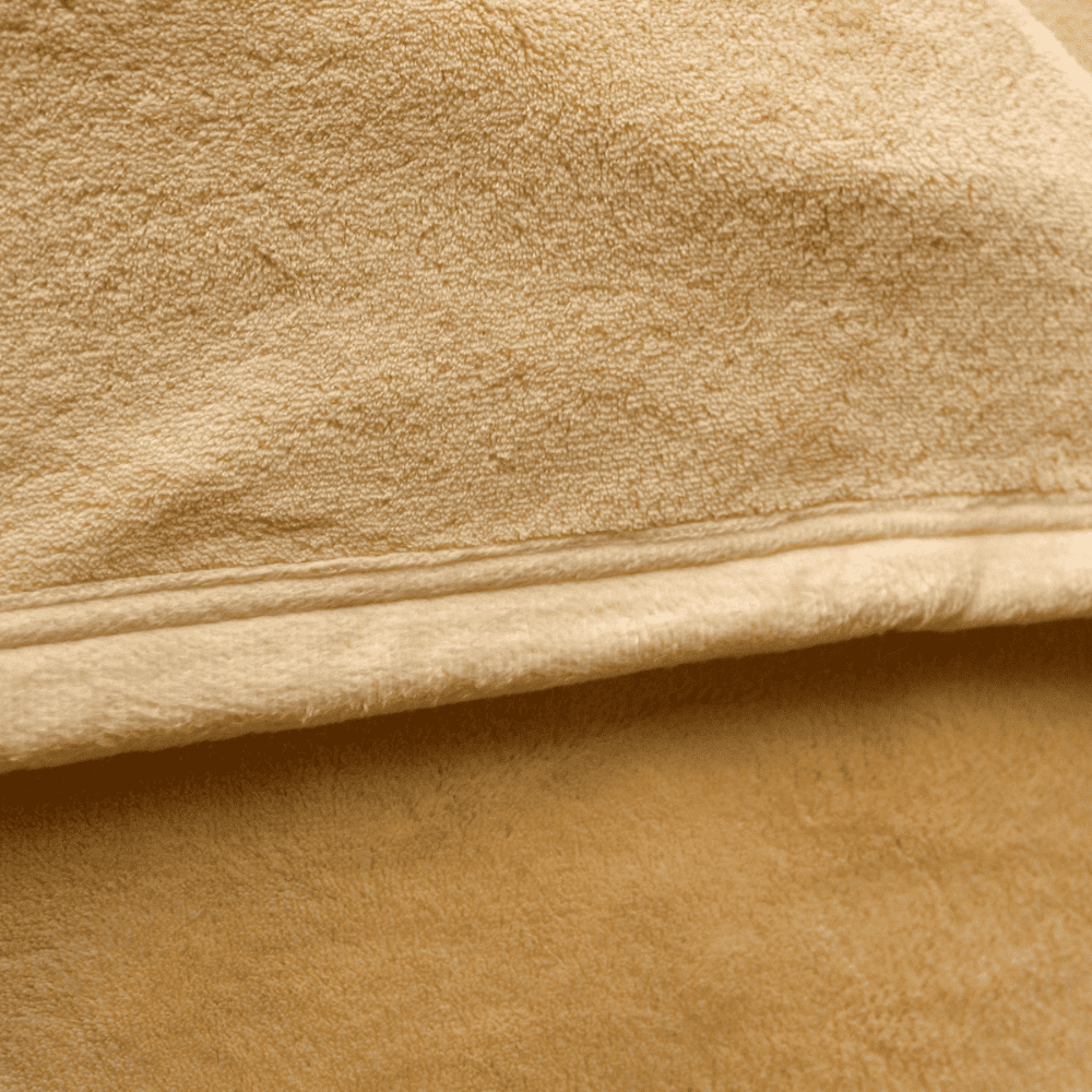 Close-up of velour fleece blanket texture in champagne color, showing plush softness and high-quality finish for luxury hotel or home use.